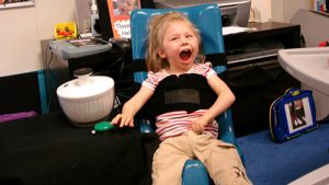 A smiling child strapped into a floor chair